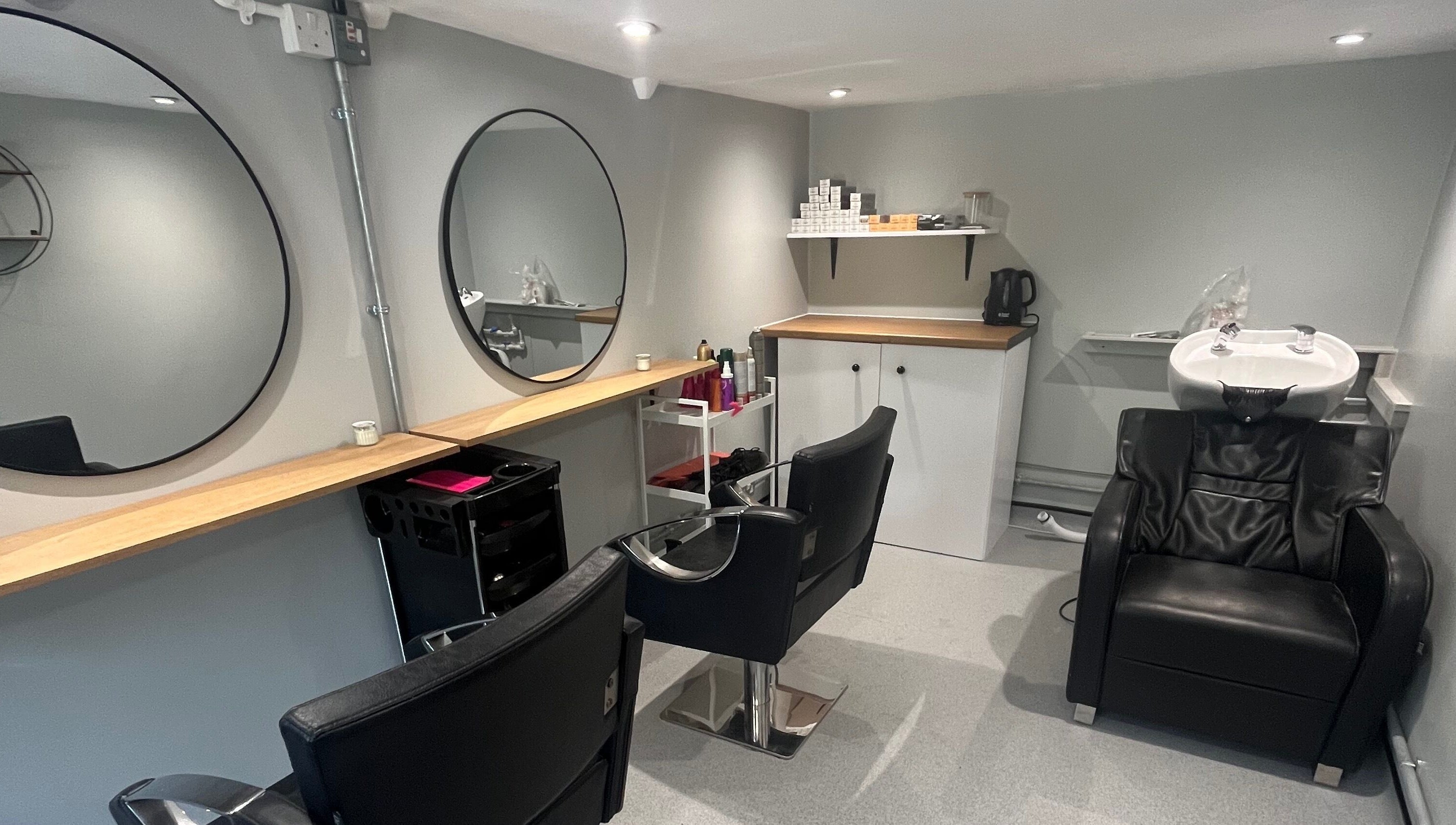 Modern salon interior at Hair By Sophie Leah, Fifield, England, GB with sleek black chairs and a wash station.
