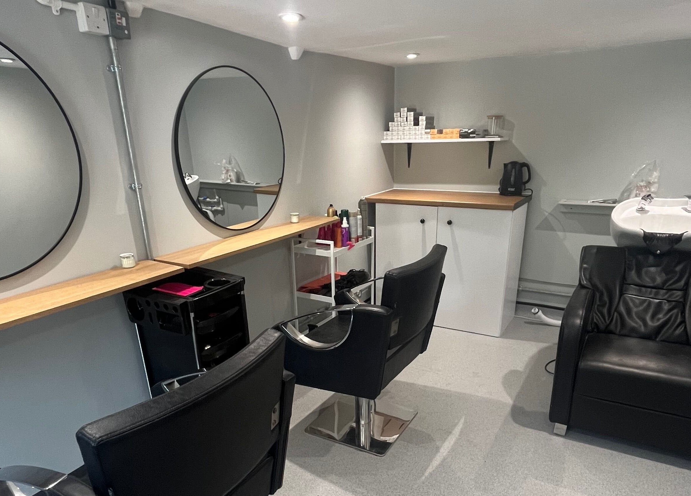 Modern salon interior at Hair By Sophie Leah, Fifield, England, GB with sleek black chairs and a wash station.