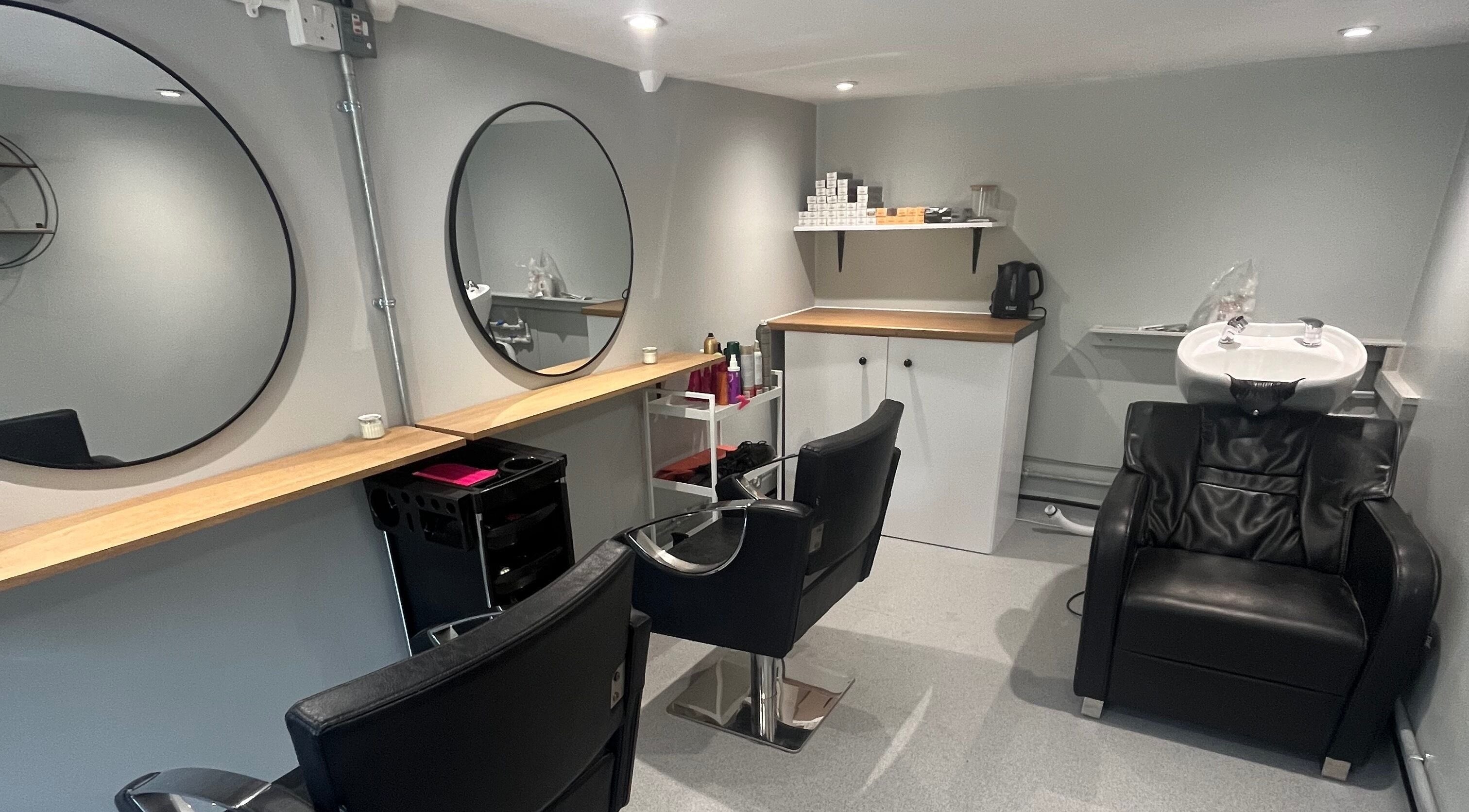 Modern salon interior at Hair By Sophie Leah, Fifield, England, GB with sleek black chairs and a wash station.