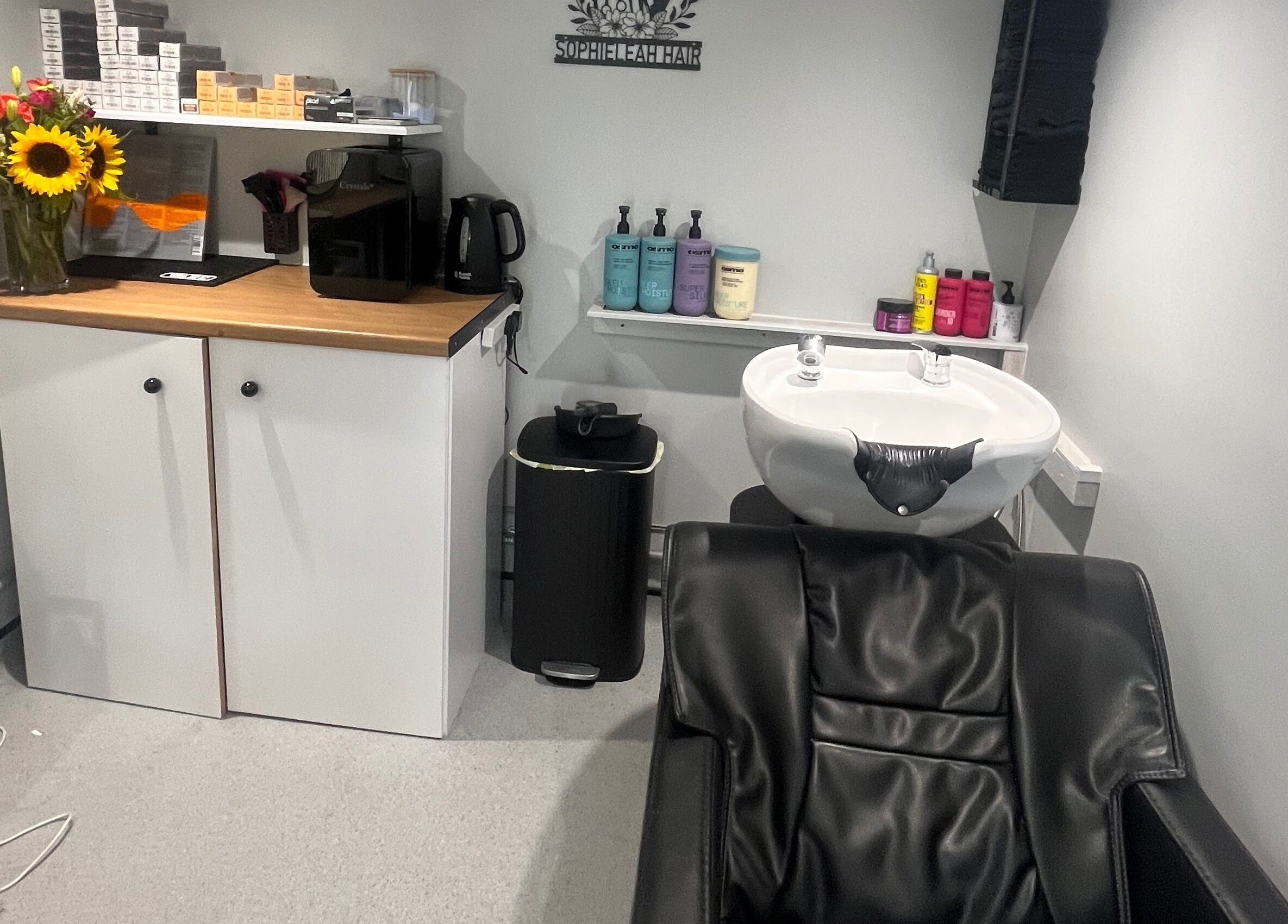 Chic salon interior at Hair By Sophie Leah, Fifield, England, GB showcasing wash station and vibrant decor.