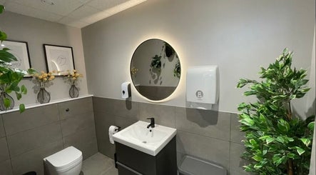 Chic restroom at Aesthetics by Katrina, London, England, GB featuring modern decor and vibrant green plants.