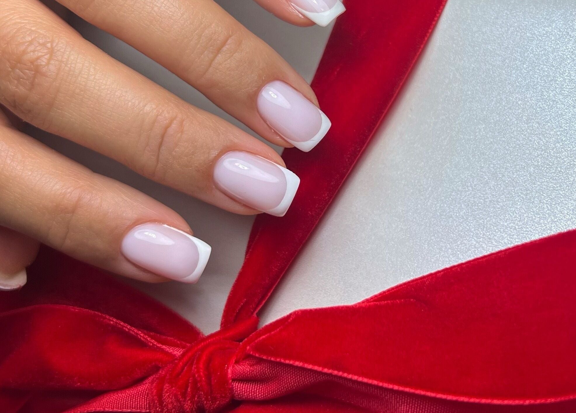 French manicure with red bow by Nails by Ilona in Chicago, United States, US.
