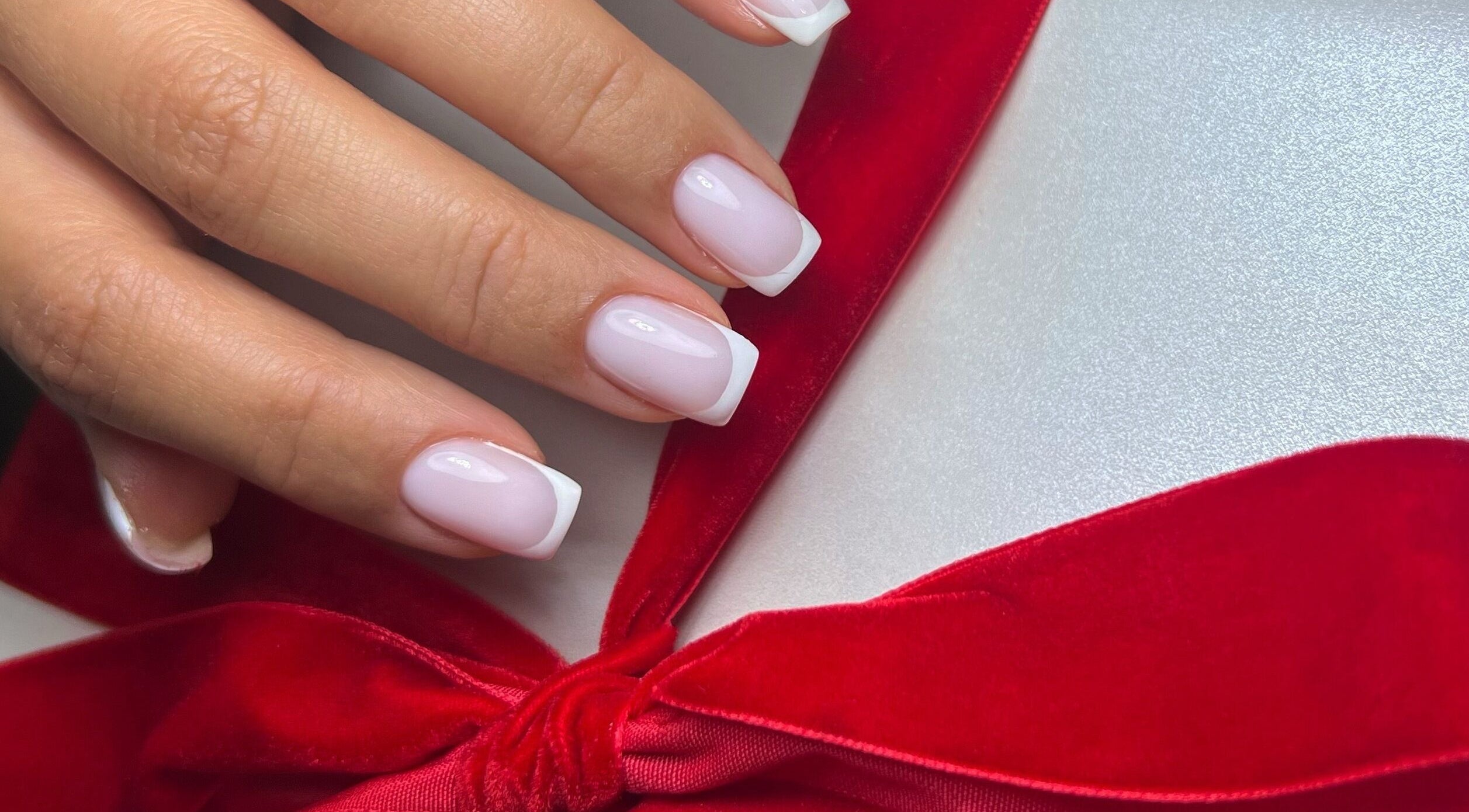 French manicure with red bow by Nails by Ilona in Chicago, United States, US.