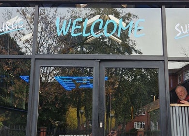Welcome sign at DŌMN THERAPY in Liverpool, England, GB, with reflective glass entrance.