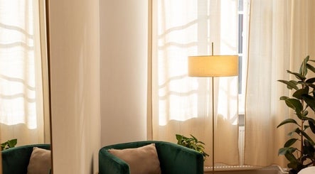 Elegancki kącik w Irkha Massage w Warszawa, Województwo Mazowieckie, PL, z zielonym fotelem i lampą.