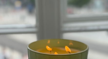 Płonąca żółta świeca w Irkha Massage, Warszawa, Województwo Mazowieckie, PL, tworzy relaksującą atmosferę.