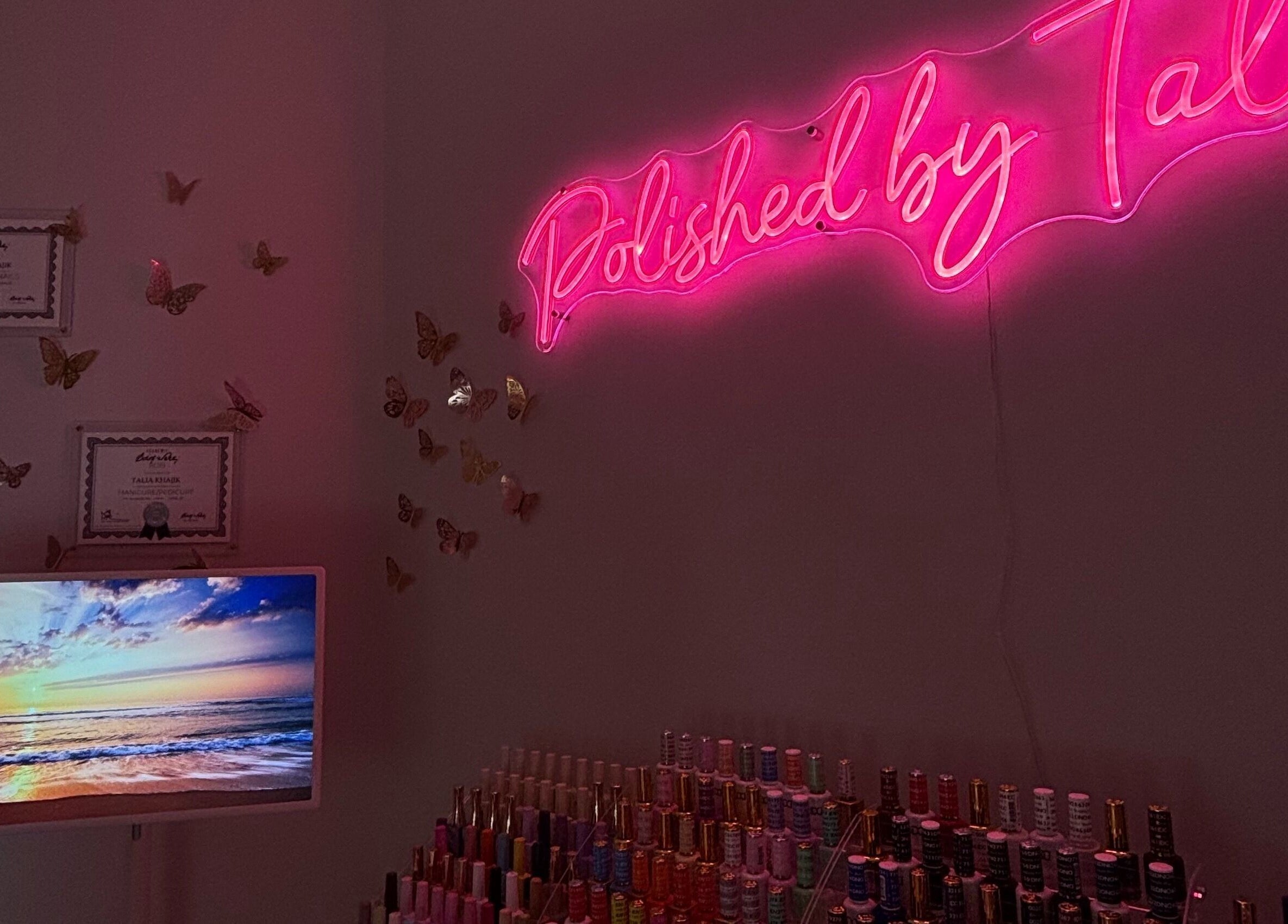 Neon sign reading 'Polished By Talia' in Laval, Québec, CA with nail polish display and certificates.