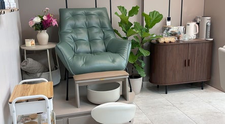 Silla de manicura verde en Nail It by Karla Belandria, Ciudad de Panama, PA, rodeada de flores y plantas.