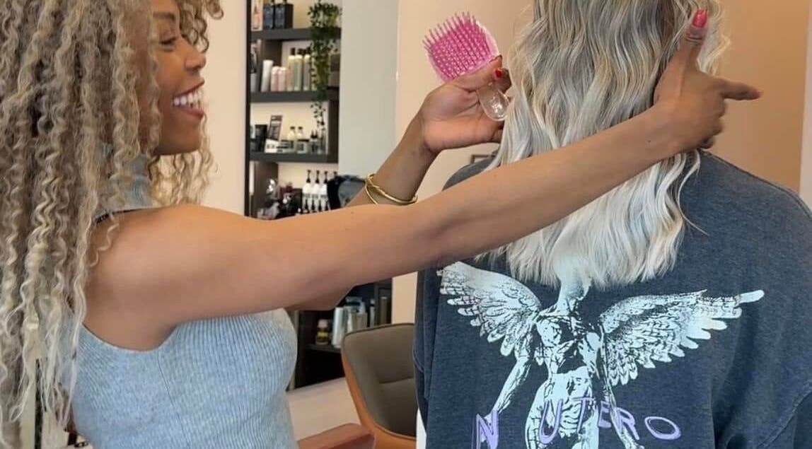 Stylist at Ursulabeauty.Co in London, England, GB creating a glamorous hairstyle with precision and care.