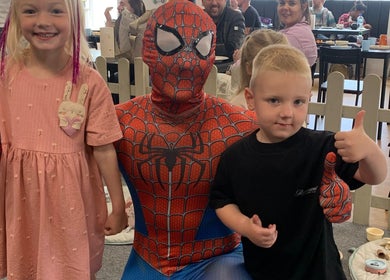 Kids smiling with a superhero character at Beautybyklw, Blackburn, England, GB.