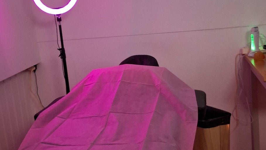 Cozy treatment room at Glow & Go in Paramaribo, Paramaribo, SR, with pink lighting and a massage table.