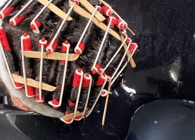 Intricate perm rods in action at Level Up Barbershop, Manchester, England, GB.