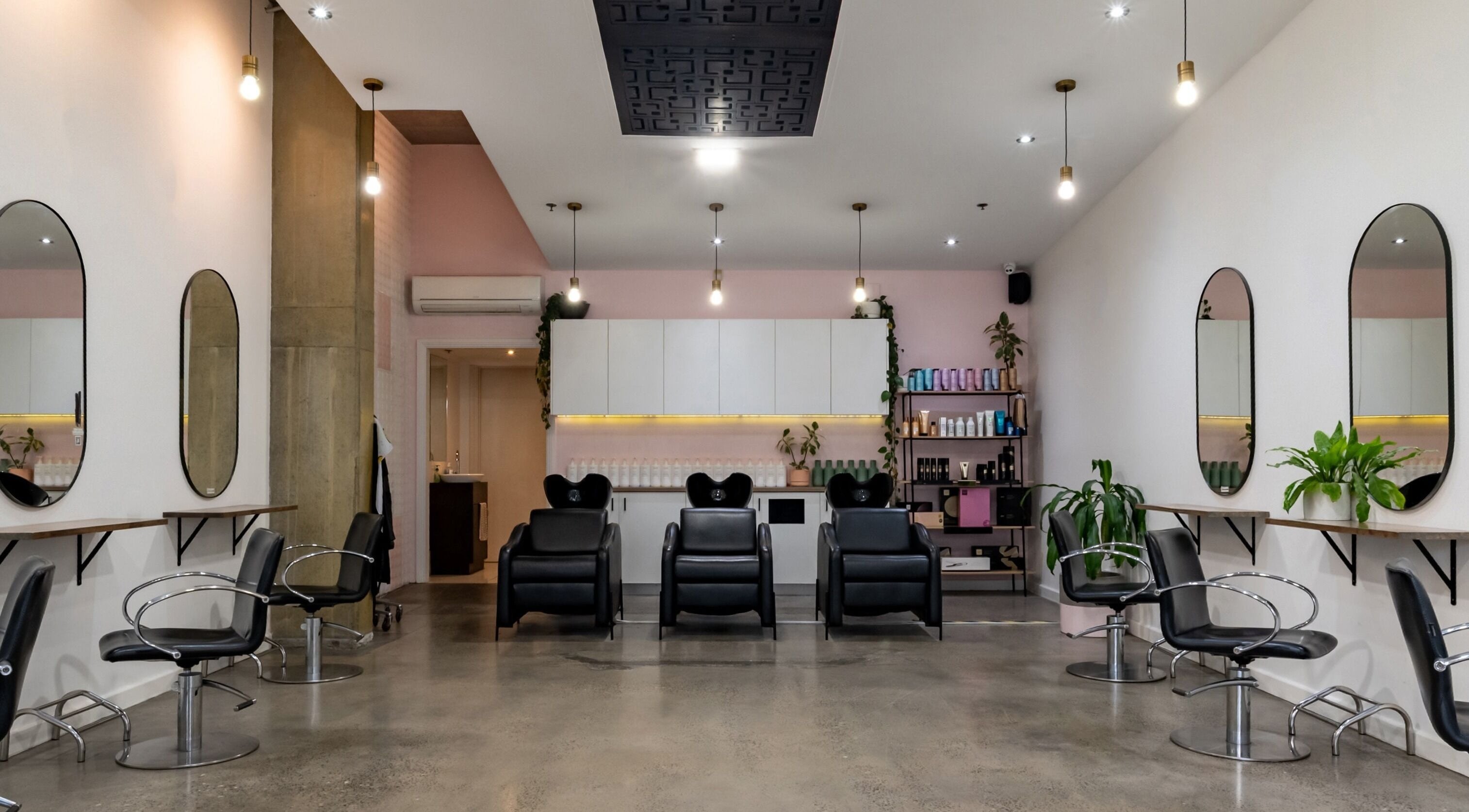 A modern, elegant salon interior at Oscar Charlie Hair, Melbourne, Victoria, AU, featuring stylish chairs and mirrors.