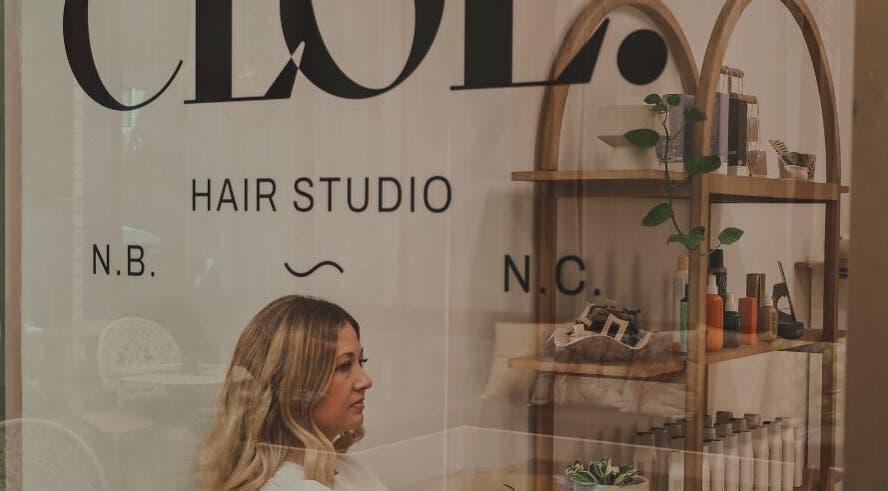 Woman inside Cloe. Hair Studio in Woolgoolga, New South Wales, AU, next to natural product shelves.