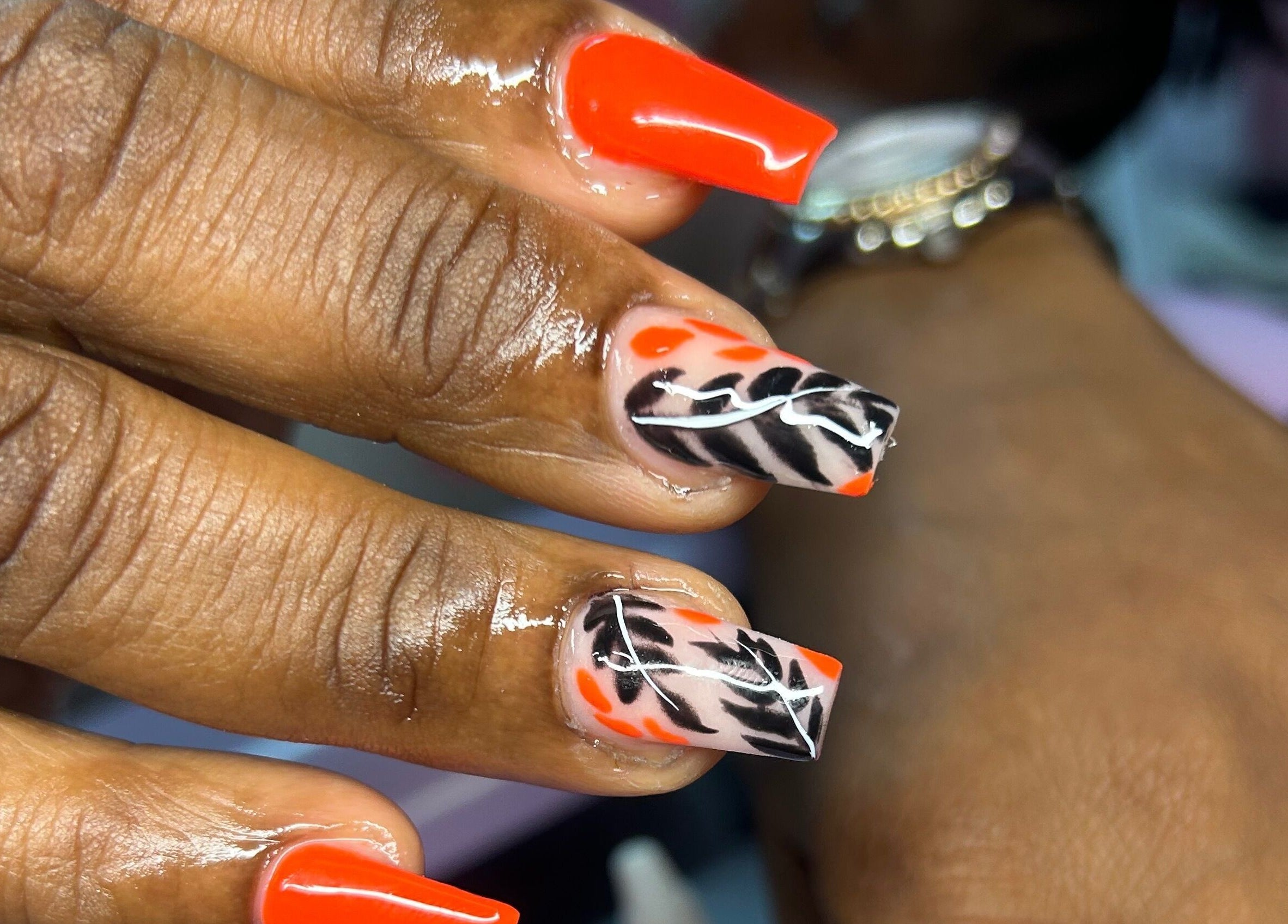Stylish nail art with orange and black design at TNP Salon, Nassau, New Providence, BS.