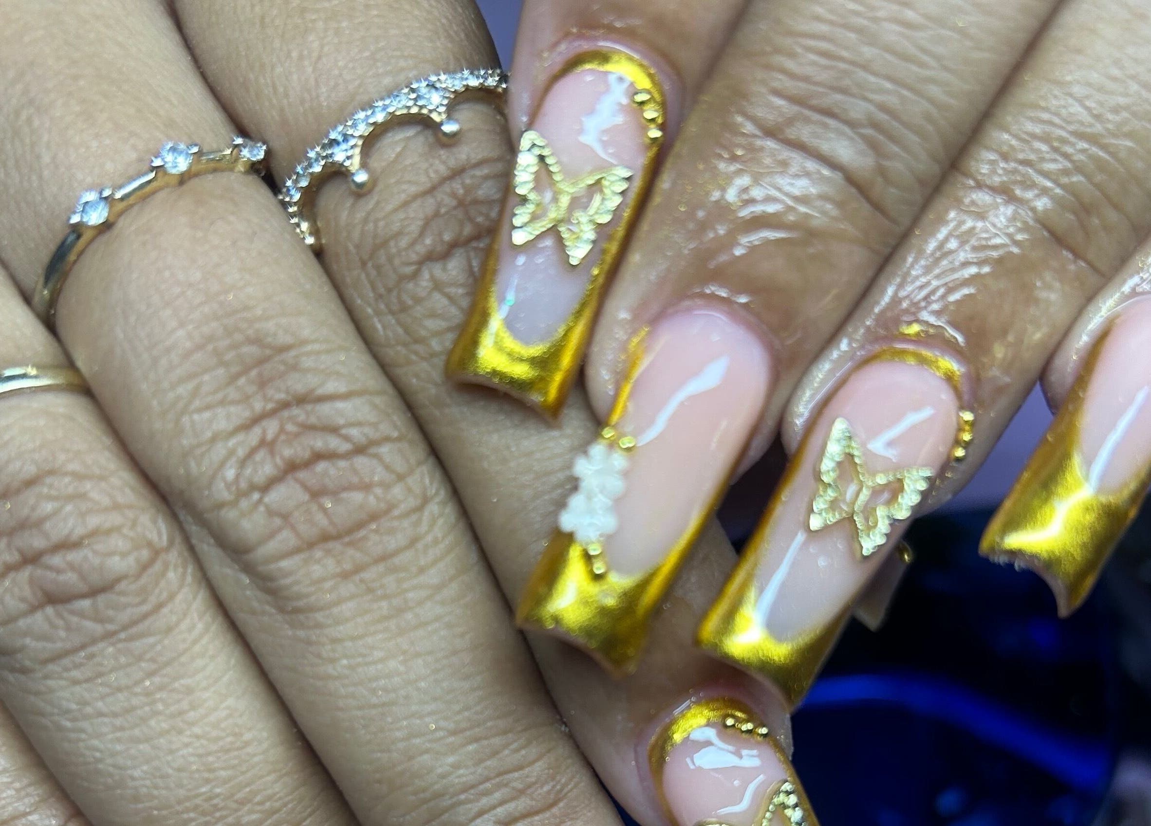 Elegant golden butterfly nails at TNP Salon, Nassau, New Providence, BS, showcasing artistic manicure design.