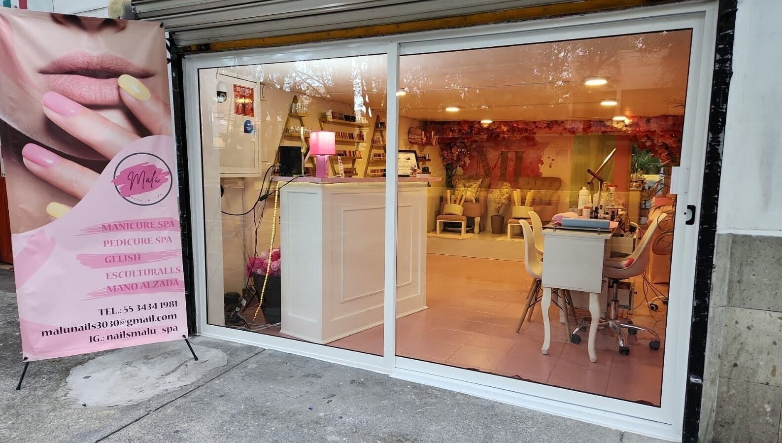 Entrada de Malú Nails&Spa, Ciudad De México, decorada con cartel publicitario de manicura y spa.
