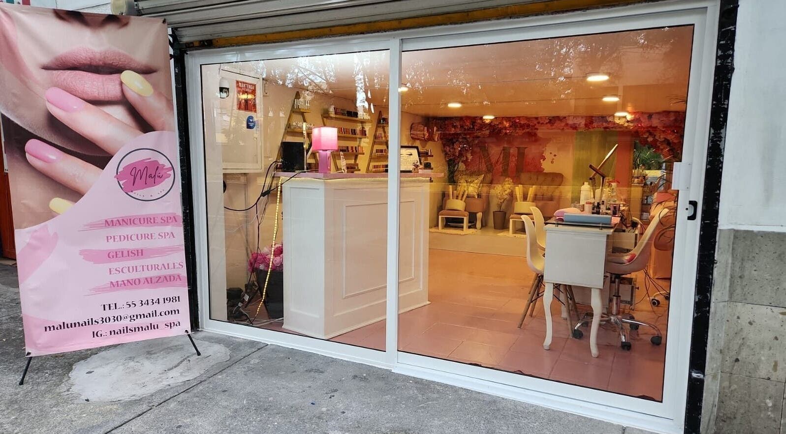 Entrada de Malú Nails&Spa, Ciudad De México, decorada con cartel publicitario de manicura y spa.