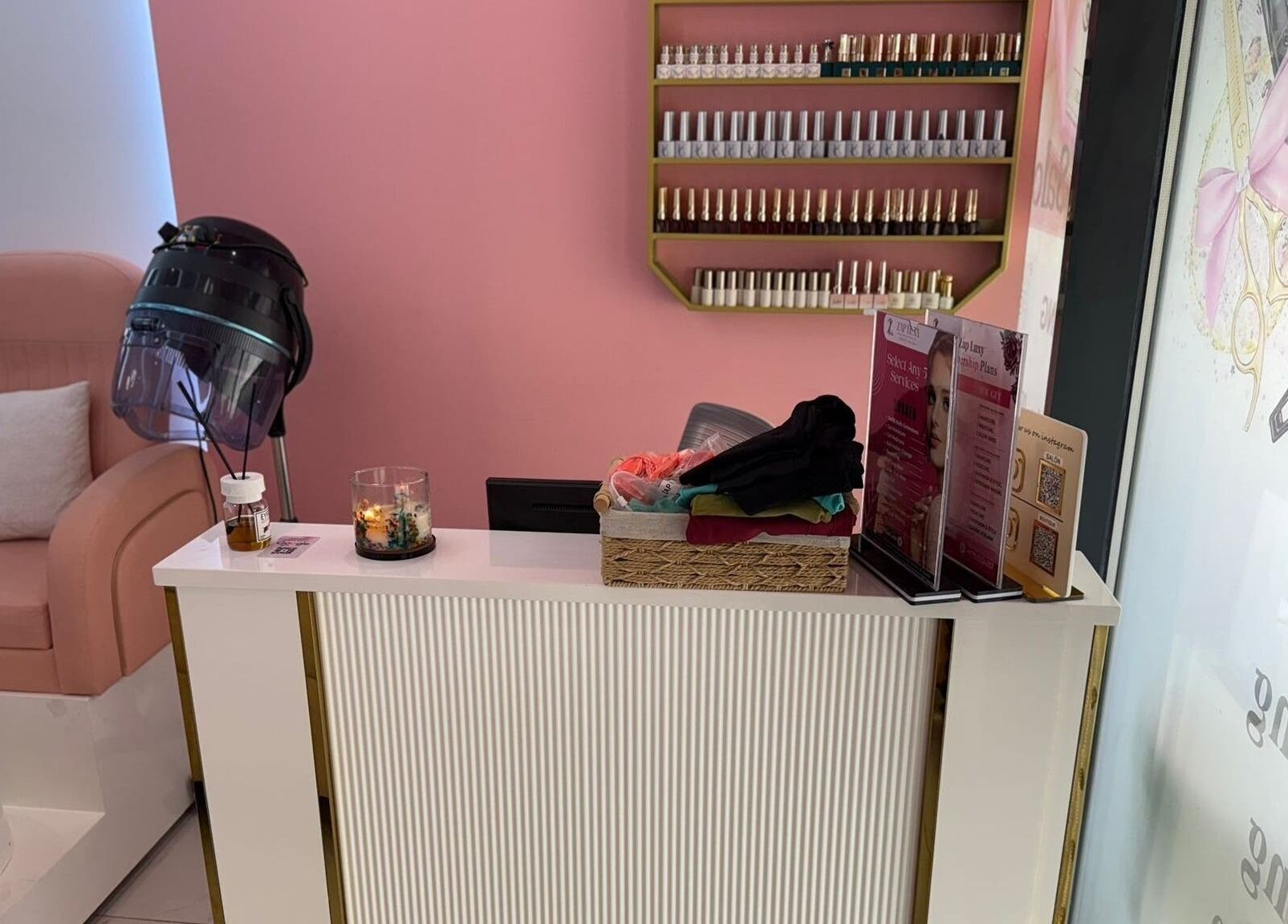 Reception area at Zap Luxy Beauty Salon, Dubai, Dubai, AE with pink chair and nail polish display.