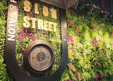 Lush wall with clock at Slon Street in abu dhabi, AE. Vibrant greenery enhances beauty and wellness ambiance.