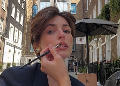 Makeup artist at Izzy.hmua in Borehamwood, GB, applying lipstick on a client outdoors.