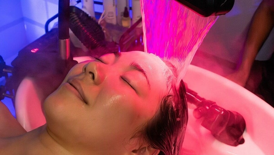Woman enjoying a Korean biotechnology face treatment at MMSTUDIO, London, England, GB under pink LED light.