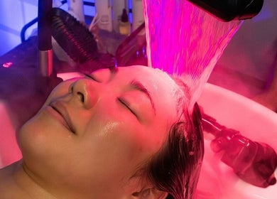 Relaxing facial treatment at MMSTUDIO | Korean Biotech Face & Scalp Programs in London, England, GB under pink light.