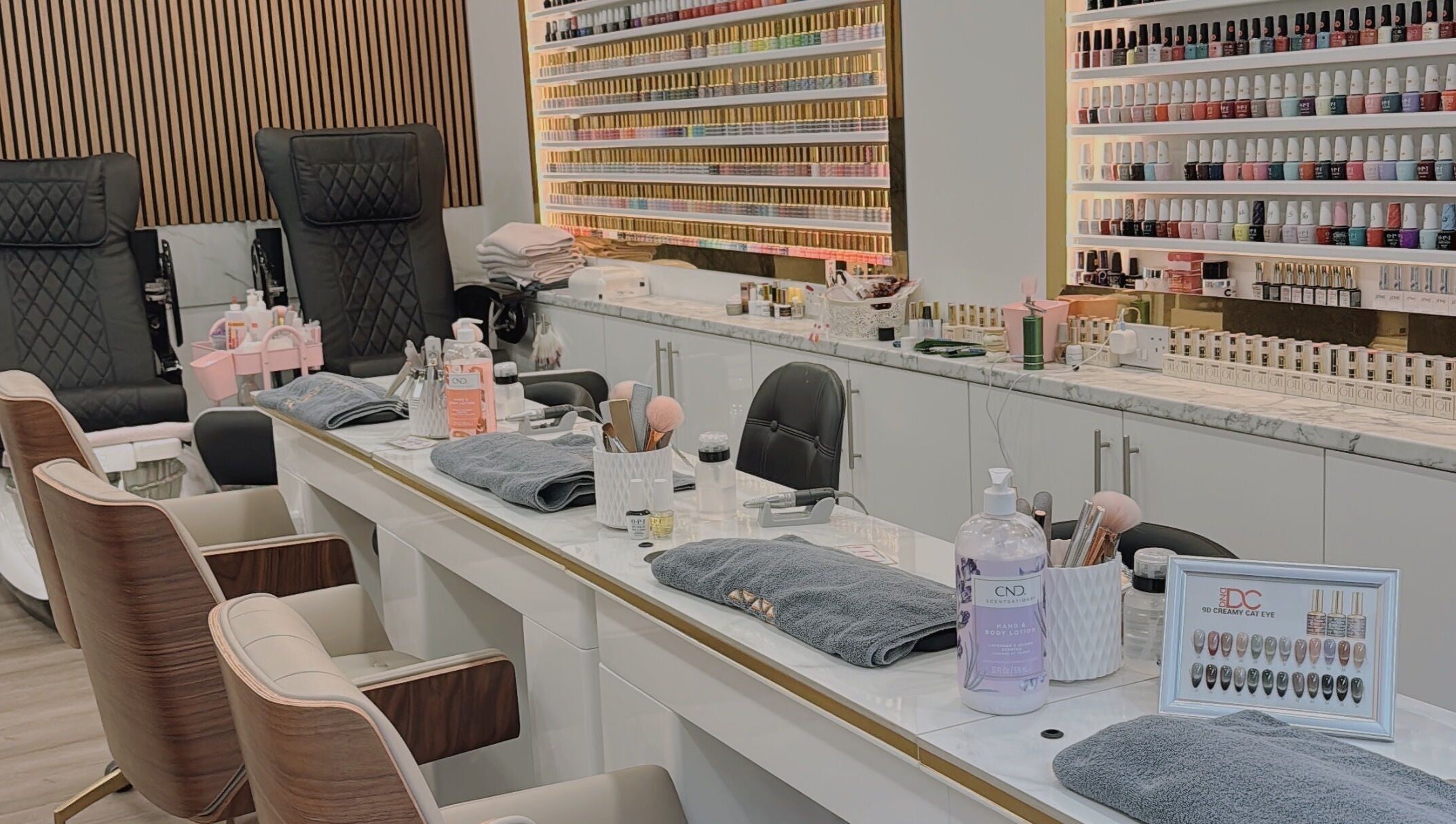 Elegant nail salon setup at Belle Ame Beauty Champagne Lounge, London, England, GB. Features plush chairs and nail polishes.