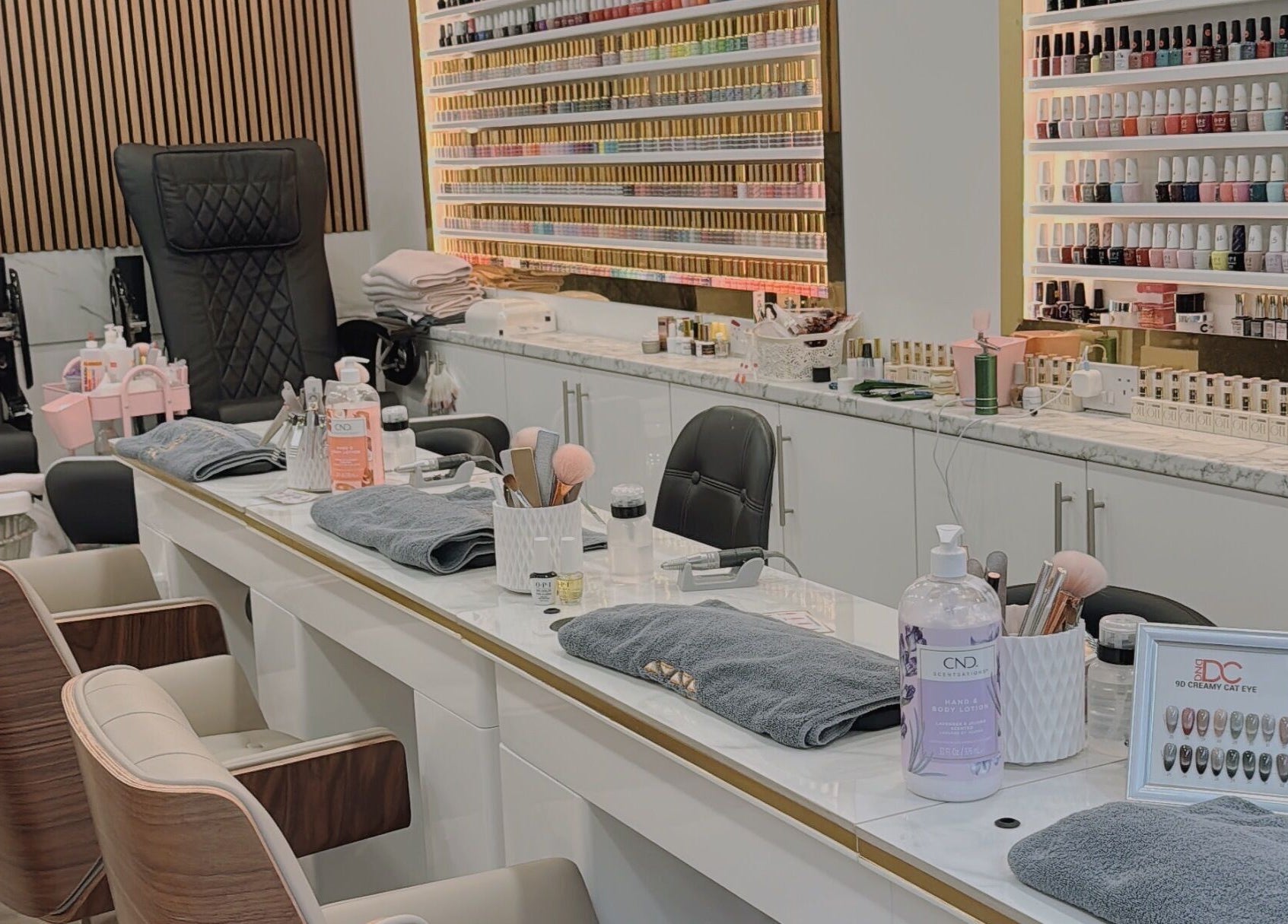 Elegant nail salon setup at Belle Ame Beauty Champagne Lounge, London, England, GB. Features plush chairs and nail polishes.