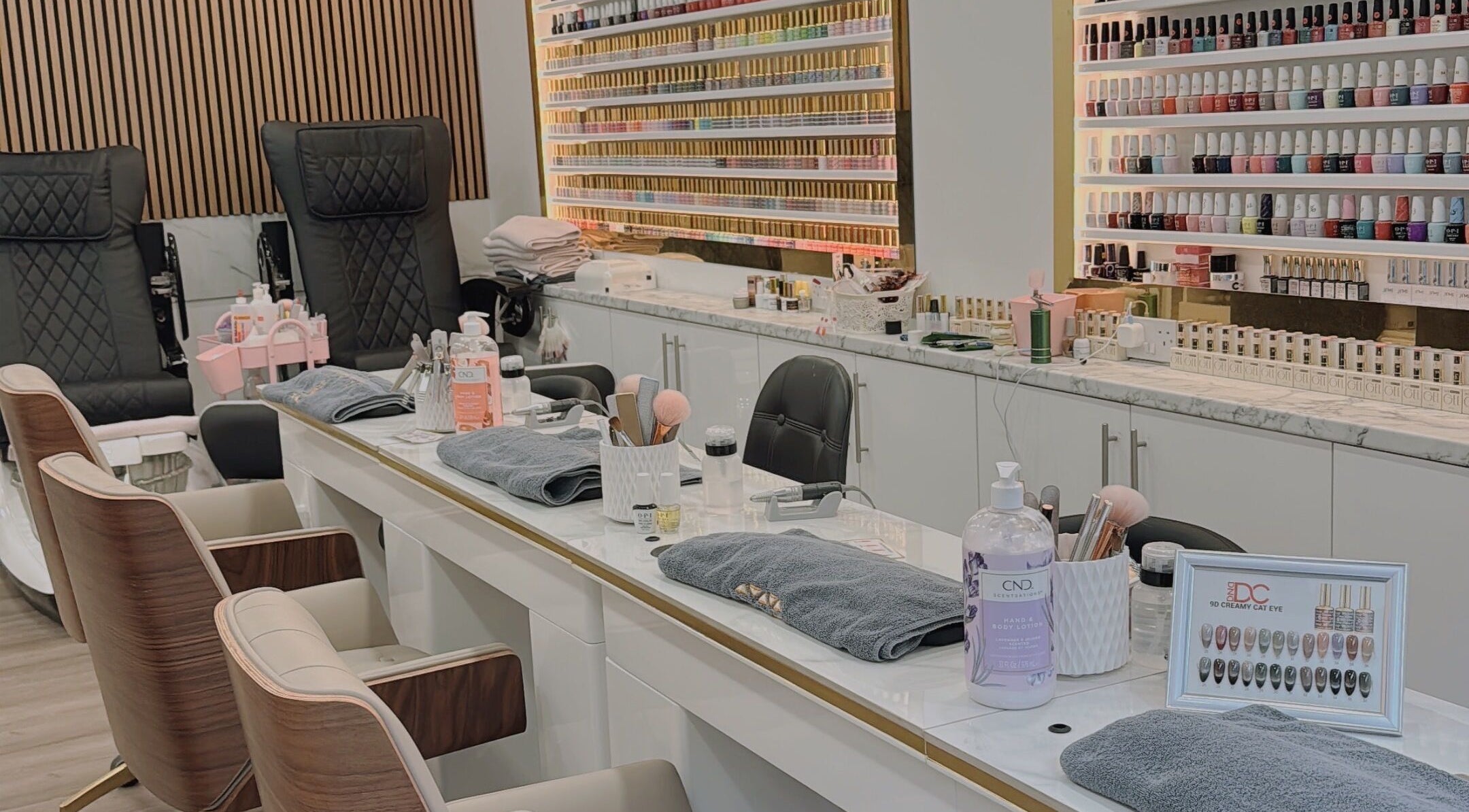 Elegant nail salon setup at Belle Ame Beauty Champagne Lounge, London, England, GB. Features plush chairs and nail polishes.