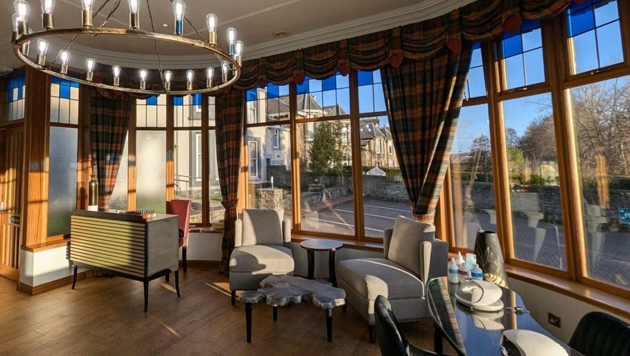 Cozy seating area at Lovat Hair Nail and Beauty, Perth, Scotland, GB with panoramic windows and elegant decor.