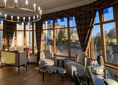 Cozy seating area at Lovat Hair Nail and Beauty, Perth, Scotland, GB with panoramic windows and elegant decor.