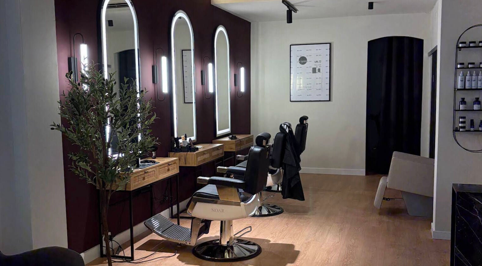 Interior moderno de Noar Barbershop en Barcelona, Cataluña, ES, con sillas de barbero y espejos iluminados.
