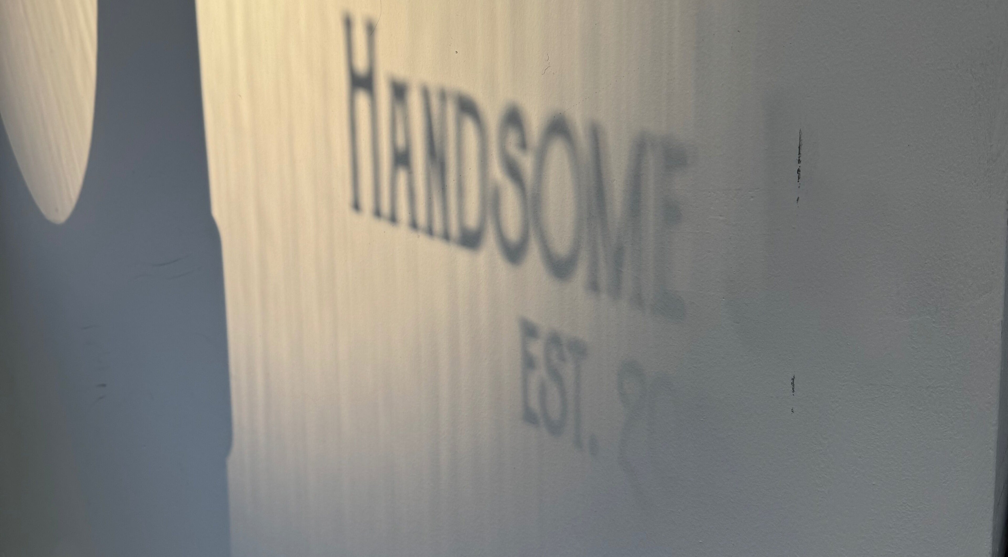 Shadow of 'Handsome' text on the wall at Handsome Jacks Finnieston, Glasgow, Scotland, GB.