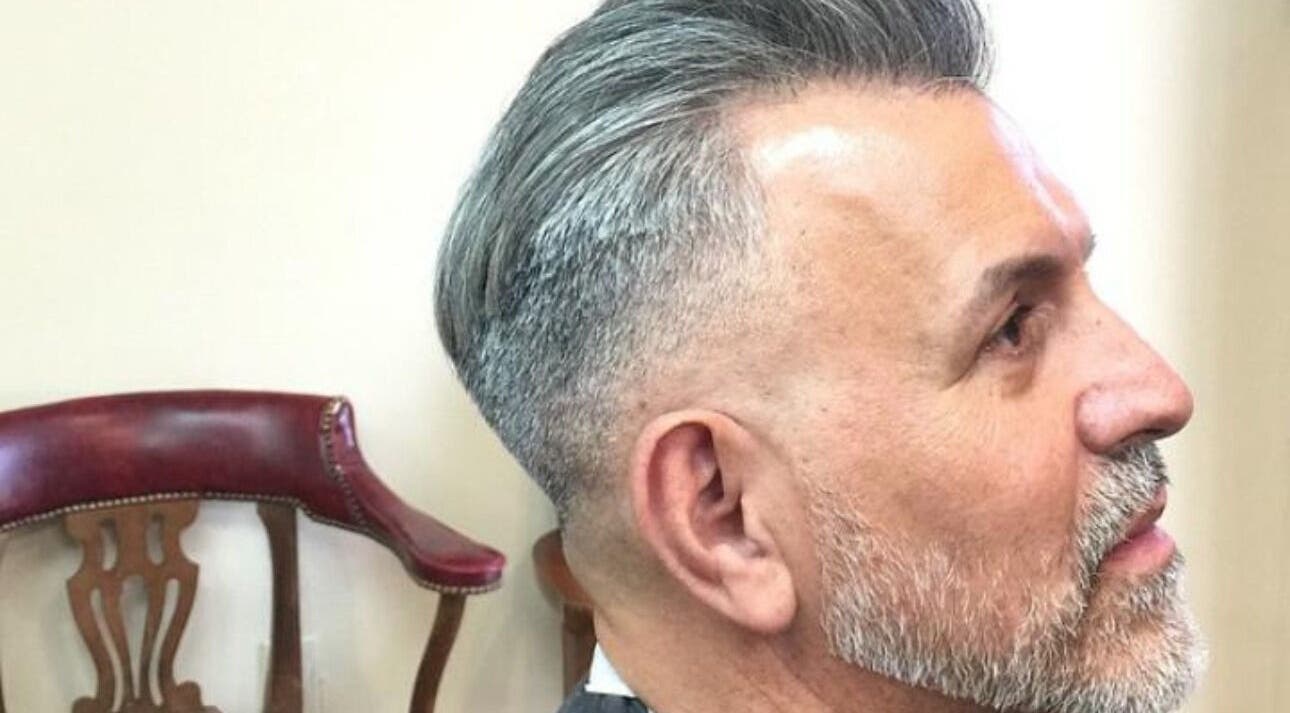 Moderne herenkapsel bij Joe Barbershop in Zwolle, Overijssel, NL. Traditionele stoel op de achtergrond.