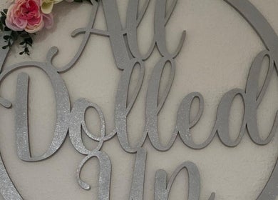 Elegant wall decor sign 'All Dolled Up' at She'la's, Hasland, England, GB adorned with flowers.