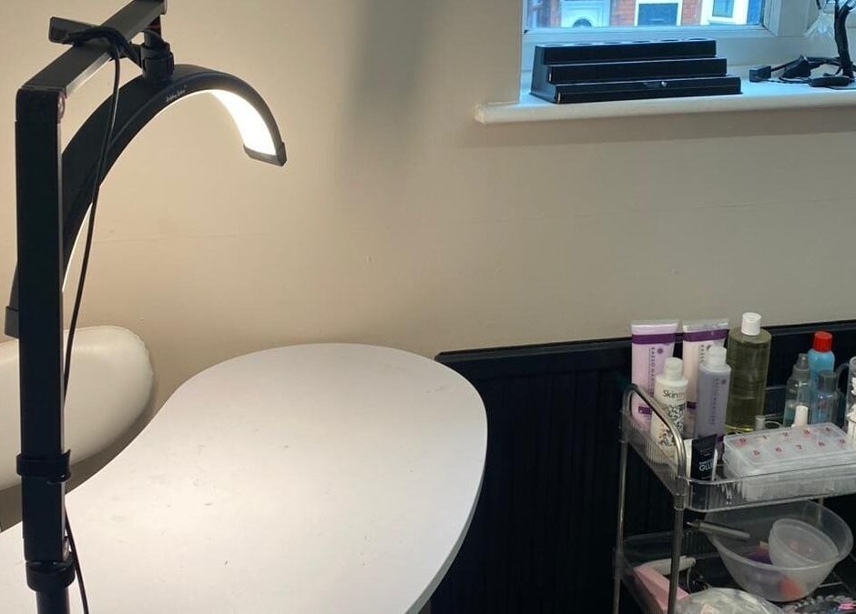 Manicure station at She'la's in Hasland, England, GB with a lamp and beauty products.
