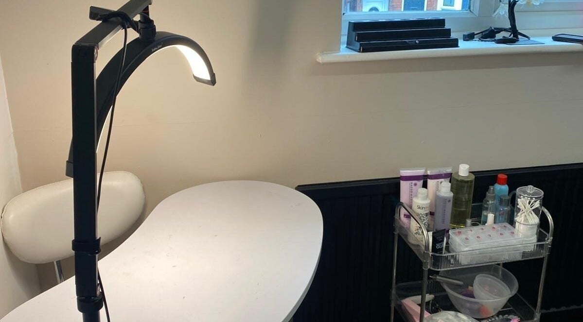 Manicure station at She'la's in Hasland, England, GB with a lamp and beauty products.