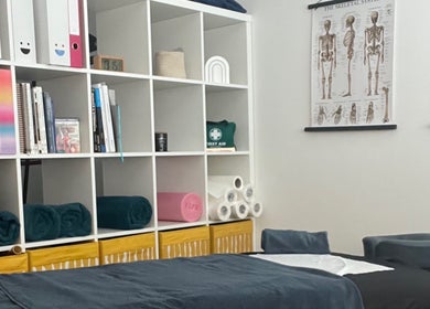Calming therapy room at TH Performance Therapy, Cornwall Sports Massage, Padstow, England, GB with charts and shelves.