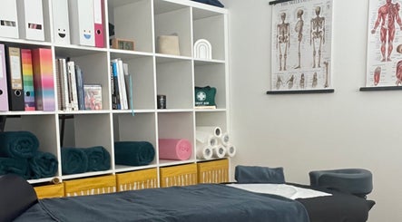 Calming therapy room at TH Performance Therapy, Cornwall Sports Massage, Padstow, England, GB with charts and shelves.