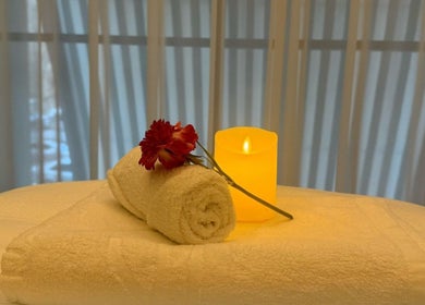 Relaxing spa setup at Swan Massage in Yuma, Arizona, US with a rolled towel, flower, and candle.