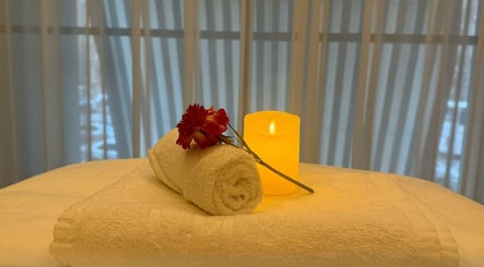 Relaxing spa setup at Swan Massage in Yuma, Arizona, US with a rolled towel, flower, and candle.