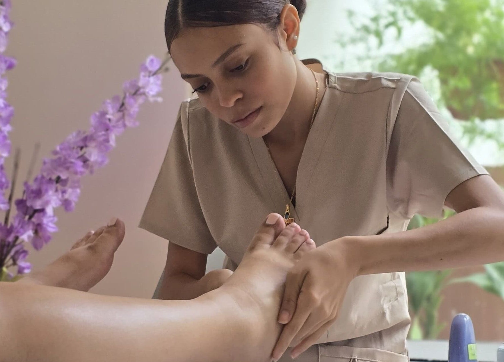 Terapista realizando masaje en Heiwa D.K, Panamá, Provincia De Panamá, PA, rodeado de flores lilas.