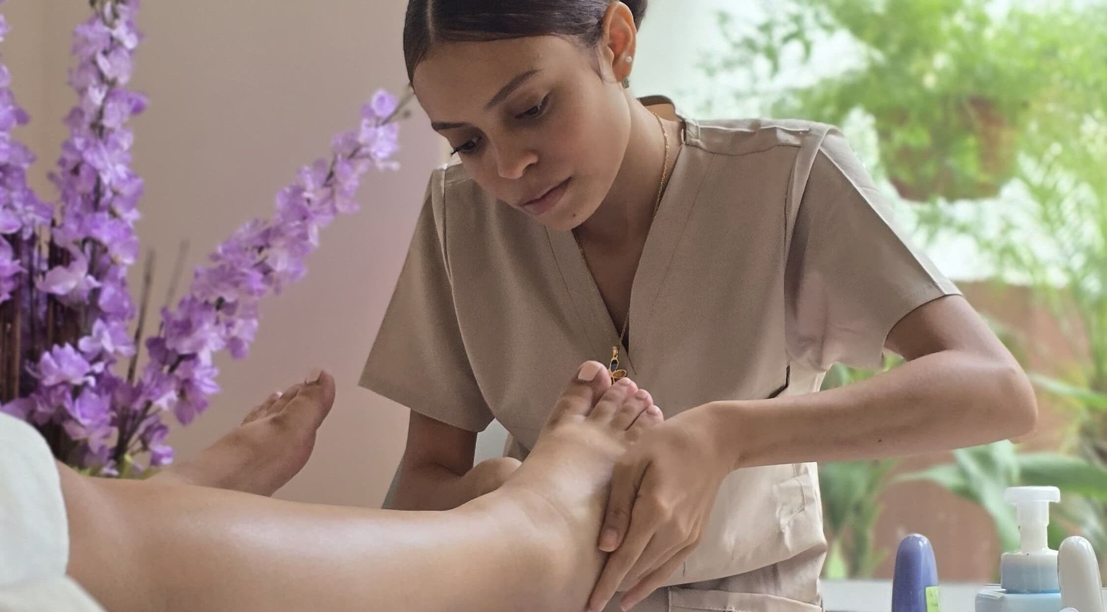 Terapista realizando masaje en Heiwa D.K, Panamá, Provincia De Panamá, PA, rodeado de flores lilas.