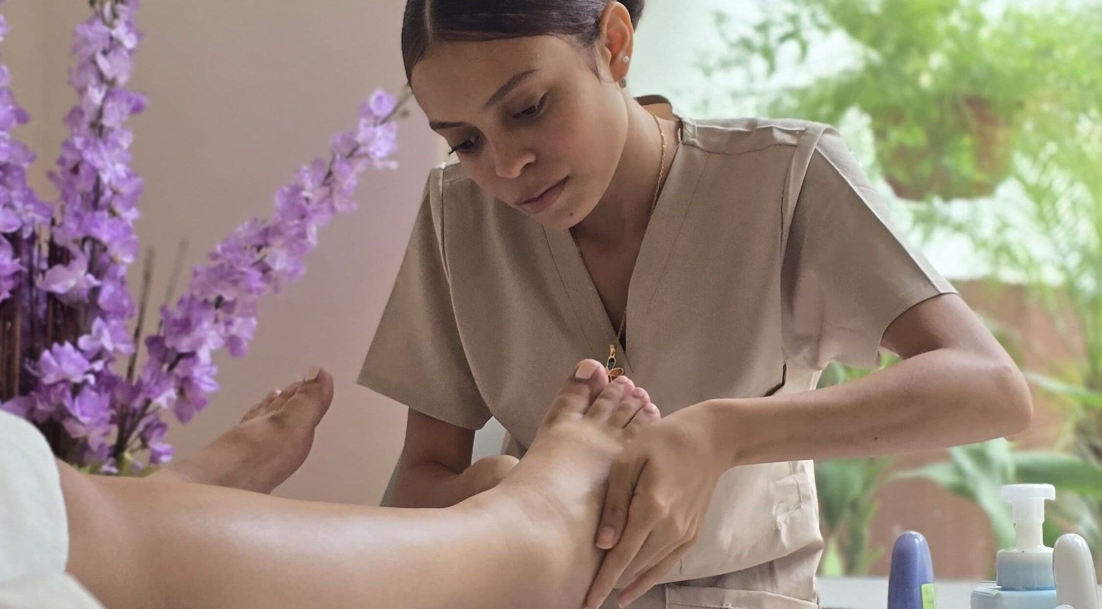 Terapista realizando masaje en Heiwa D.K, Panamá, Provincia De Panamá, PA, rodeado de flores lilas.