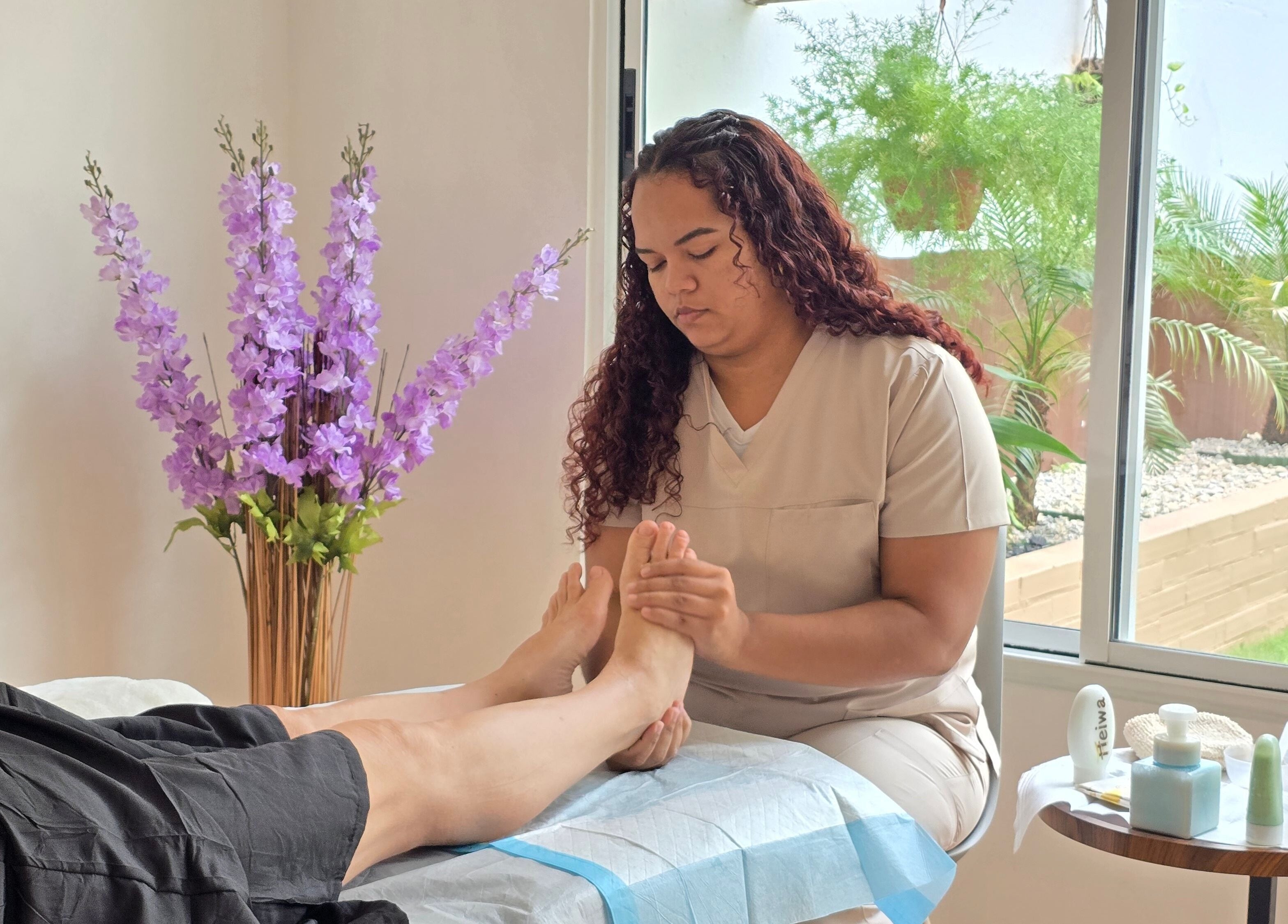 Terapista realiza masaje podal en Heiwa D.K, Panamá, Provincia De Panamá, PA, rodeado de plantas.
