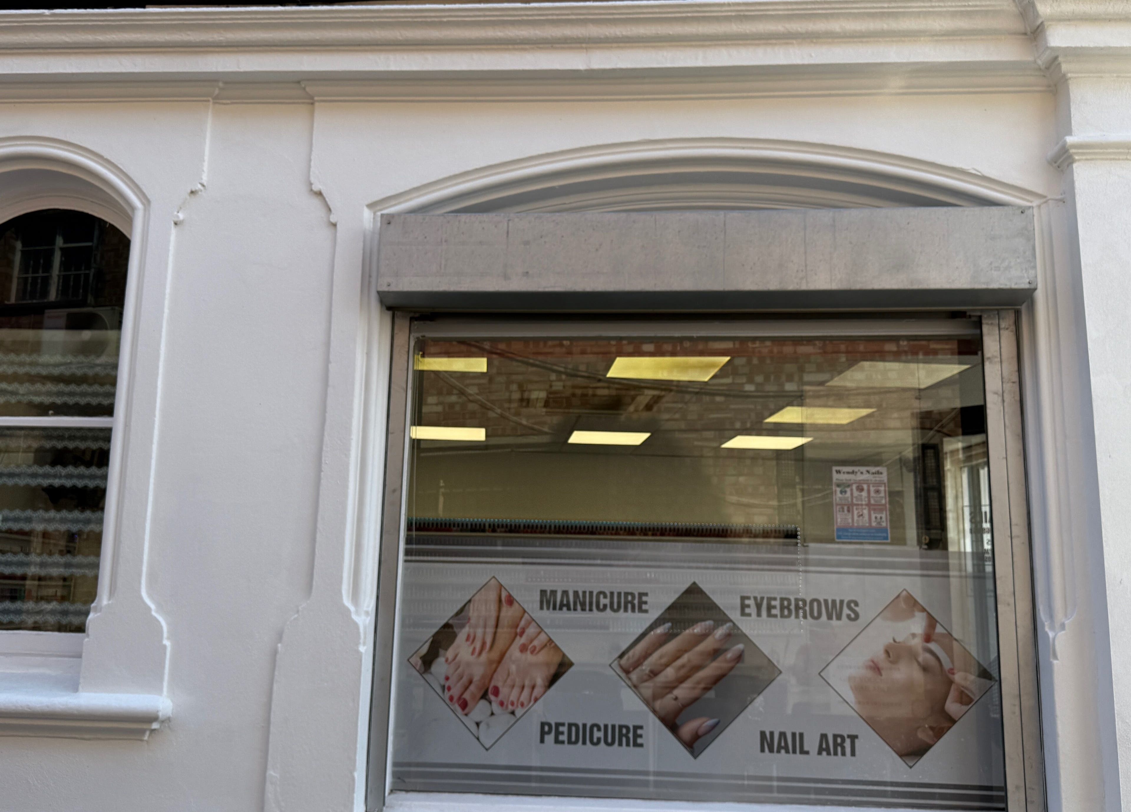 Front window of Wendy’s Nails in Kettering, England, GB, showcasing services: manicure, pedicure, eyebrow, nail art.