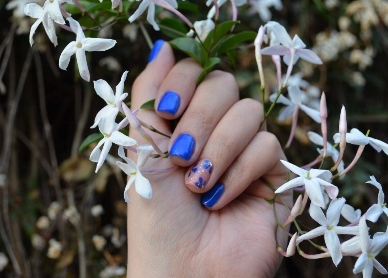 Vibrant blue and floral nail art at The Tipsy Pixie, Roodepoort, Gauteng, ZA, surrounded by white flowers.