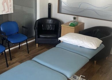 A tranquil massage room at CP Sports Massage Therapy, Kenfig Hill, Wales, GB, featuring cozy chairs and a massage bed.