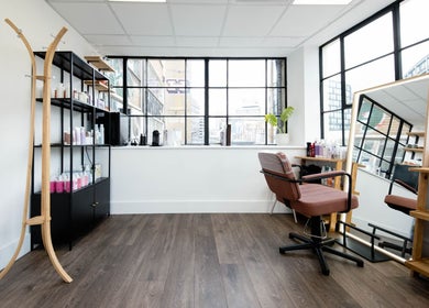 Spacious interior of Logvina Hair, London, England, GB with modern styling chair and large mirror.